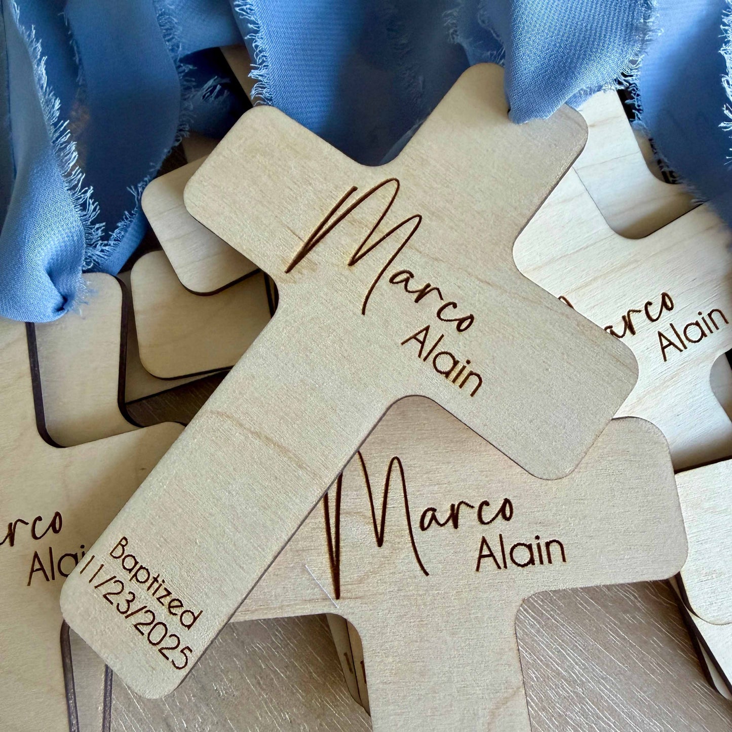 Multiple engraved baptism favor crosses with dusty blue chiffon ribbons