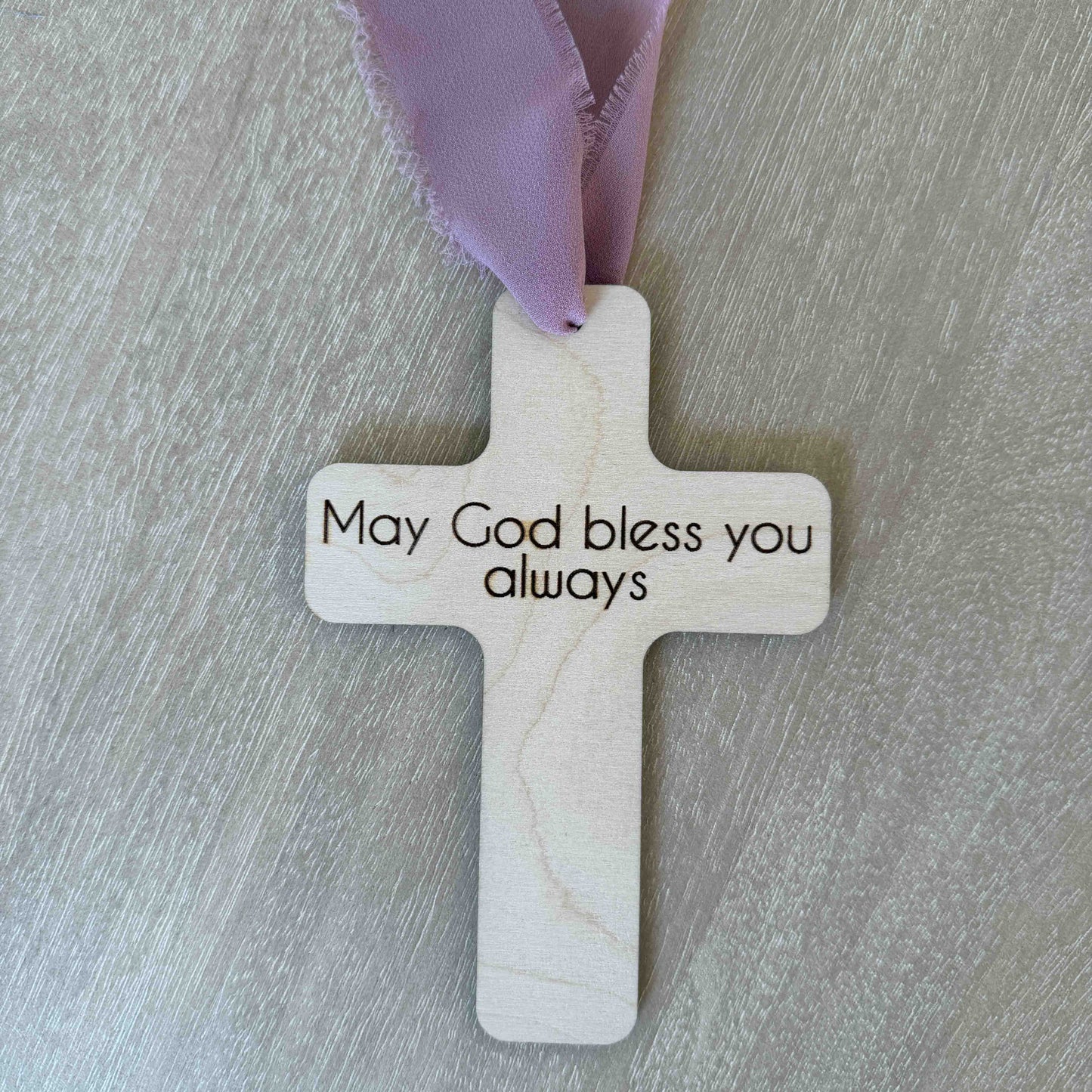 Personalized baptism favor cross with message on back mauve chiffon ribbon on wood background