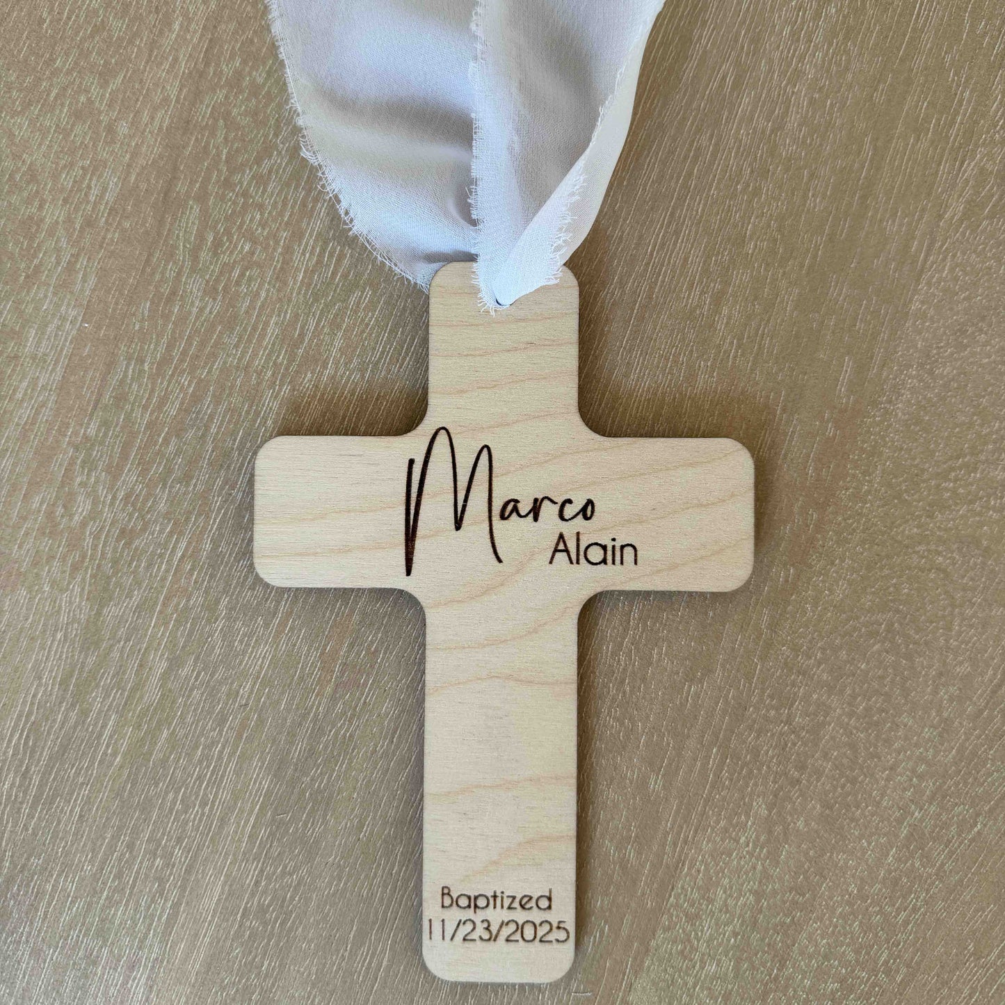Personalized baptism favor cross with white chiffon ribbon on wood background