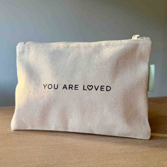 Canvas pouch with minimalist black text reading “You Are Loved.”