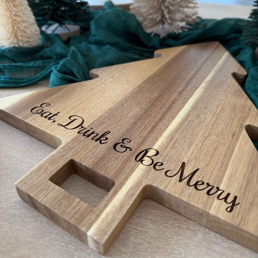 Close-up of laser engraved Eat, Drink & Be Merry on acacia Christmas tree serving board