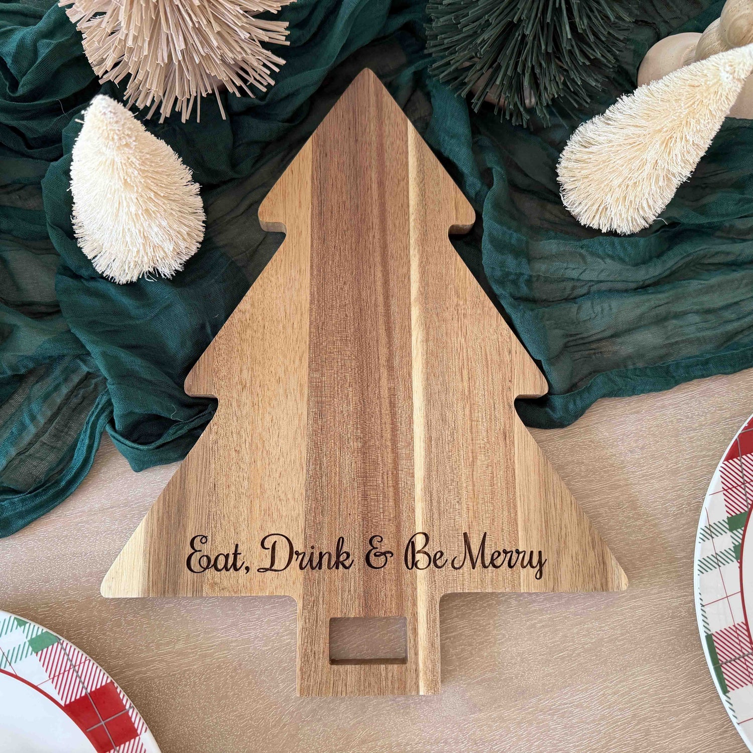 Acacia wood Christmas tree shaped serving board with engraved holiday phrase Eat, Drink & Be Merry
