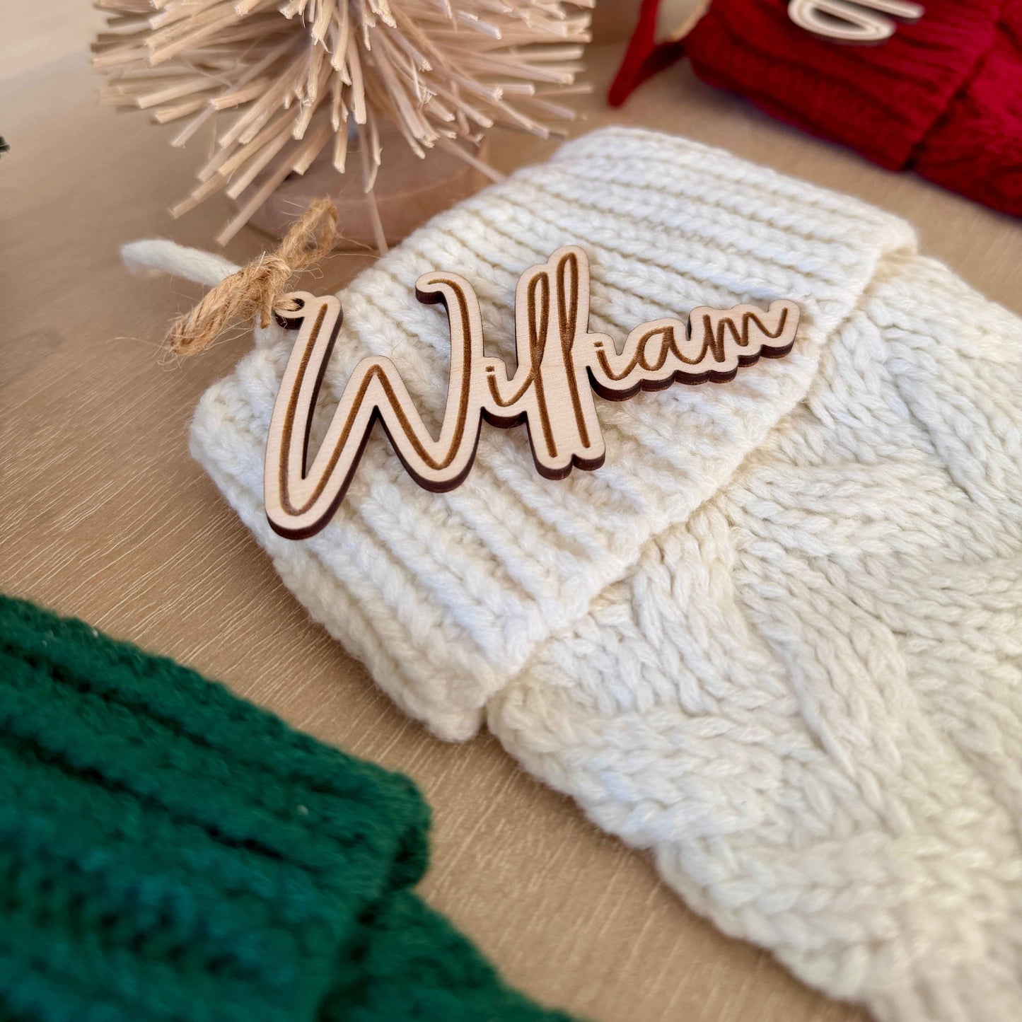 White / Ivory knit Christmas stocking with personalized wooden script name tag reading “William,” tied on with rustic jute twine.