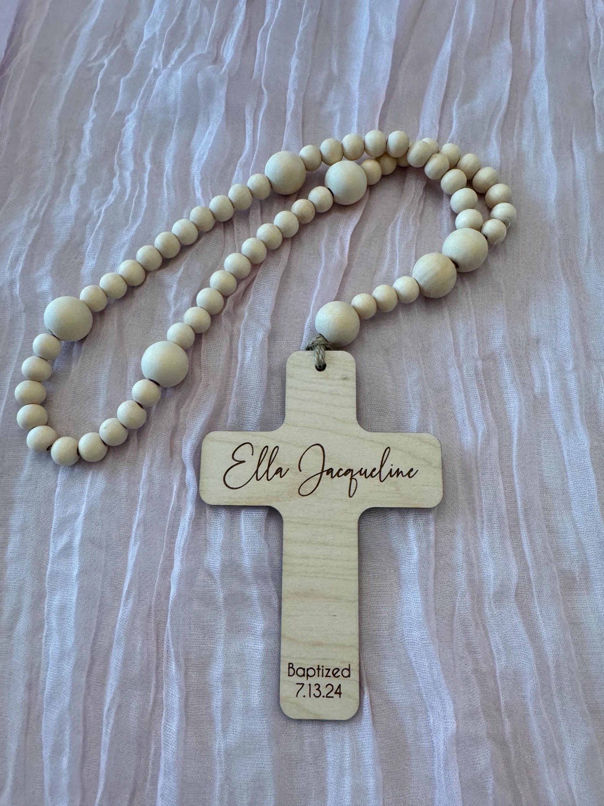 Handcrafted wooden rosary with natural beads and engraved cross displayed on white background.
